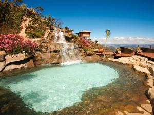 a swimming pool with a waterfall in a backyard at Pousada Estalagem do Mirante in Brumadinho