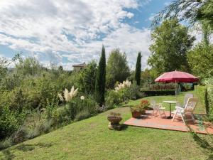 un jardín con mesa, sillas y sombrilla en Villa in Tuscany with Pool near Certaldo, en Gambassi Terme