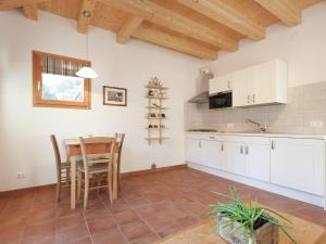 CesiomaggioreにあるBelvilla by OYO Flat with outdoor bubble bathの白いキャビネット、テーブルと椅子付きのキッチンが備わります。
