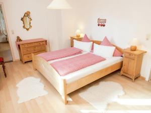 Apartment near the Feldberg ski area في Dachsberg im Schwarzwald: غرفة نوم مع سرير خشبي كبير مع وسائد وردية
