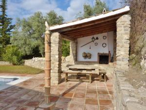 una barbacoa de piedra con mesa de picnic en un edificio de piedra en Belvilla by OYO Hoyo del Lino, en Villanueva de la Concepción