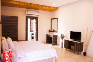 a bedroom with a white bed and a television at Riverarch Greenfields Resort in Chandwaji