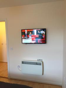 a flat screen tv hanging on a white wall at 6 Varis Apartments in Forres