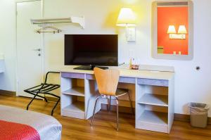 a room with a desk with a television and a bed at West Ashley Inn in Charleston