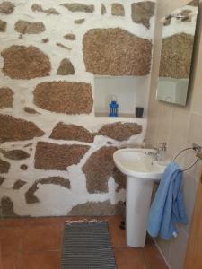 a bathroom with a stone wall with a sink at Quinta da Barroquinha in Vale de Prazeres