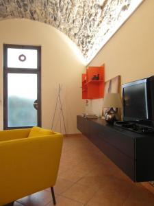 ein Wohnzimmer mit einem gelben Stuhl und einem TV in der Unterkunft La Casa di Andrea - by MyHomeInComo in Como