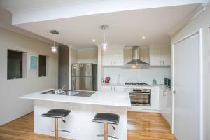 a kitchen with white cabinets and black stools at Indian Ocean Retreat in Alkimos