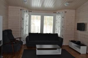 sala de estar con sofá negro y ventana en Ruoke Holiday Village, en Kesälahti