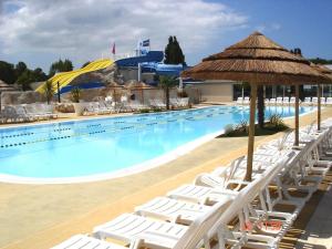 a swimming pool with white lounge chairs and a resort at Beau mobilhome La Palmyre 4 étoiles in Les Mathes