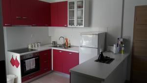 a kitchen with red cabinets and a white refrigerator at Apartment Lebedina in Kaštela
