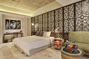 Timez Hotel Melaka في ميلاكا: غرفة نوم بسرير وطاولة واريكة