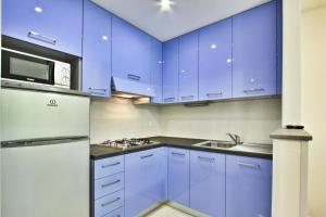 niebieska kuchnia ze zlewem i lodówką w obiekcie Condominio Libeccio w Lignano Sabbiadoro