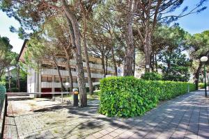 budynek z drzewami i chodnikiem z przodu w obiekcie Condominio Libeccio w Lignano Sabbiadoro