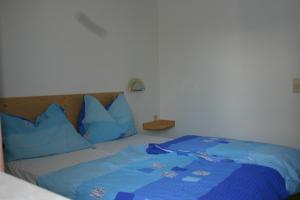 een bed met blauwe kussens en een blauwe deken bij Bungalows Karin in Sankt Kanzian
