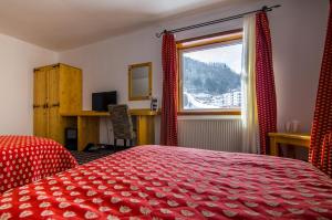 a bedroom with a red bed and a window at Resort Cheile Gradistei Moieciu in Moieciu de Sus