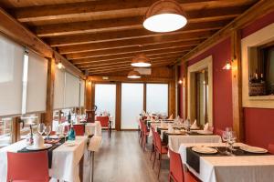 a dining room with white tables and red chairs at Hotel Palacio Muñatones in Muskiz