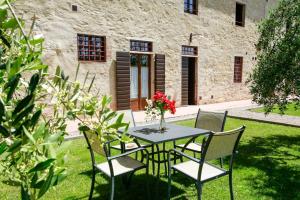 a table with chairs and a vase with flowers on it at Fattoria Abbazia Monte Oliveto in San Gimignano