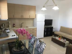 a kitchen and a living room with a table with flowers at Boussetil Apartment in Tinos