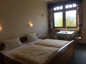 a bedroom with two beds and a table and a window at Moselhotel Lesura in Lieser