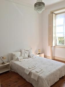 a white bedroom with a bed with two towels on it at Apartamento Casino Praia in Figueira da Foz