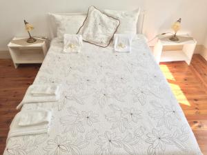 a bed with a white blanket with flowers on it at Apartamento Casino Praia in Figueira da Foz