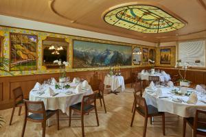 a restaurant with white tables and chairs and a painting at Hotel Ambassador in Brig