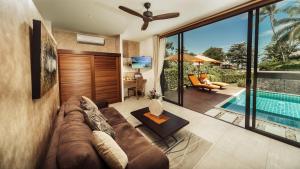 a living room with a couch and a swimming pool at Khwan Beach Resort - Luxury Glamping and Pool Villas Samui - Adults Only - SHA Extra Plus in Mae Nam
