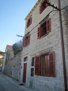 an old stone building with red shutters on a street at Vila Sipan in Šipanska Luka