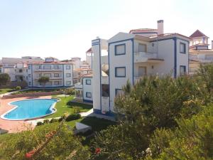 an apartment with a swimming pool and buildings at Apartamento Moura - Praia D’El Rey Golf, Surf & Beach Resort in Casal da Lagoa Seca