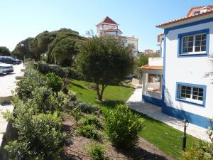 a building with a yard with trees and a tower at Apartamento Moura - Praia D’El Rey Golf, Surf & Beach Resort in Casal da Lagoa Seca