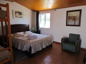 a bedroom with a bed and a chair and a window at Quinta Do Forno in Vimeiro