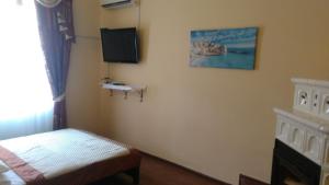 a bedroom with a bed and a tv on the wall at Кімнати в центрі in Uzhhorod