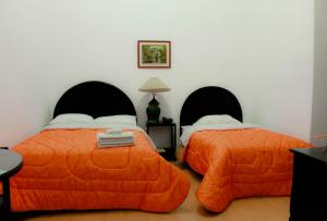 a bedroom with two beds with orange comforters at Hotel Casablanca in Cajamarca