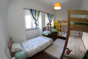 a bedroom with two bunk beds and a desk at Native Surfhouse in Praia da Areia Branca
