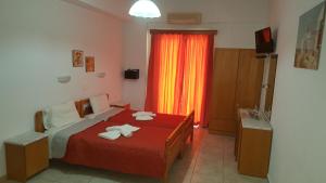 a bedroom with a red bed with towels on it at Sofia Studios & Apartments in Georgioupolis
