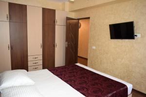 a bedroom with a bed and a flat screen tv at Apartment Ovidius - by the beach in Constanţa