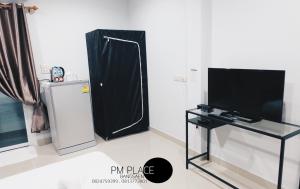 een woonkamer met een televisie en een zwart gordijn bij PM Place in Bangsaen