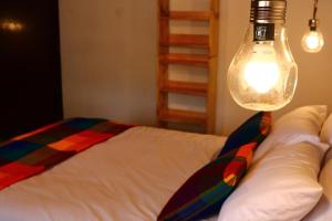 um quarto com uma cama com uma luz sobre ela em Hospedaje Los Ponchos em Otavalo