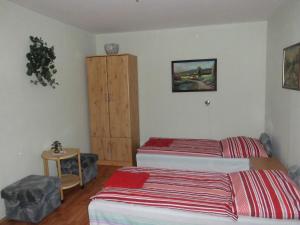 a bedroom with two beds and a wooden cabinet at Fenyves Apartman in Sárospatak