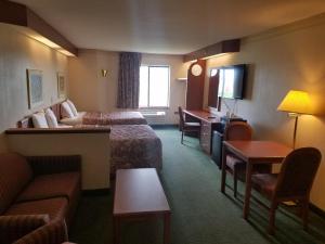 Habitación de hotel con 2 camas y sofá en Syracuse Inn and Suites, en Syracuse