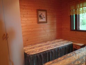 Habitación con cama en una cabaña de madera en Koskelon Lomamökit, en Rääkkylä