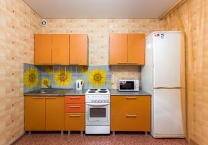 cocina con armarios naranjas y nevera blanca en Apartment 45 Str. Divizii 108 en Voronezh