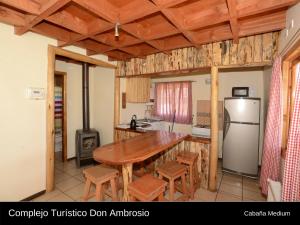 een keuken met een houten tafel en een koelkast bij Cabanas Turismo Don Ambrosio in El Manzano