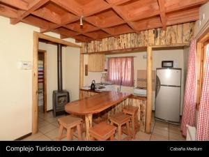 cocina con mesa de madera y nevera en Cabanas Turismo Don Ambrosio, en El Manzano