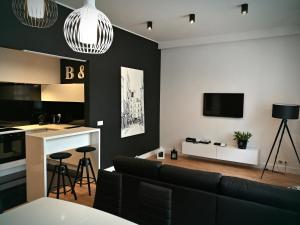 a living room with a black couch and a kitchen at Black&White Apartment- Wierzbowa 5 in Poznań