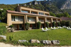 a building with a bunch of lounge chairs in the yard at Vacancéole - Le Domaine de Chames - Pont d'Arc in Vallon-Pont-dʼArc