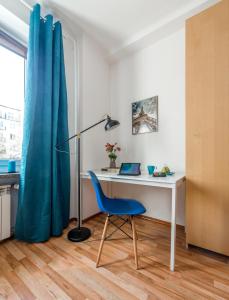 un escritorio con una silla azul junto a un escritorio con una cortina azul en P&O Apartments Waszyngtona, en Varsovia