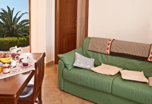 un divano verde in un soggiorno con tavolo di Agriturismo Sa Suerera a Olmedo