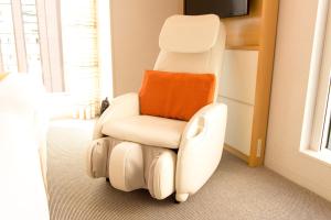 a white reclining chair with an orange pillow at remm Hibiya in Tokyo