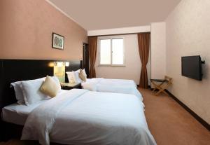 a hotel room with two beds and a television at Xin Hua Hotel Guangzhou in Guangzhou